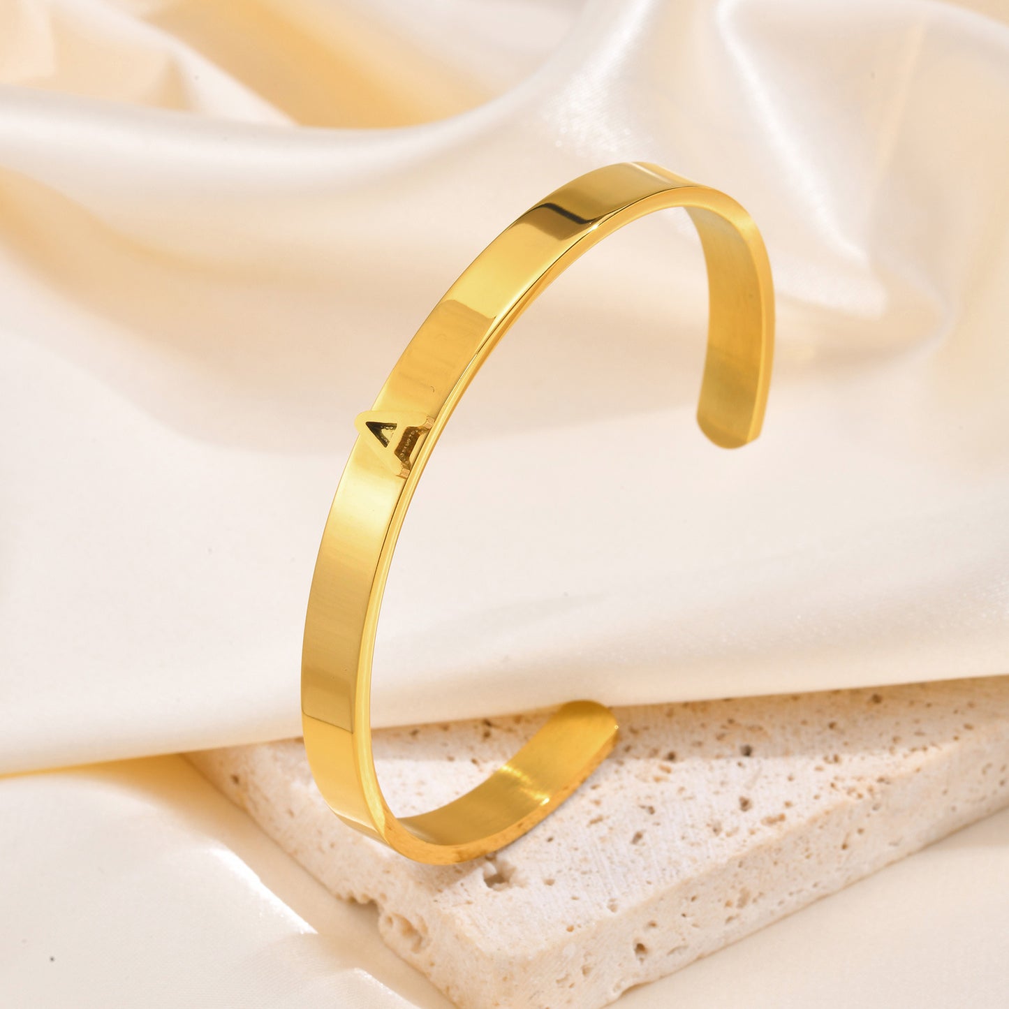 Gold alphabet bracelet on a soft beige fabric background